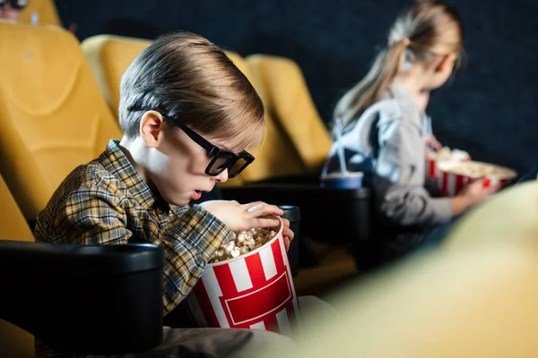 Selective focus of cute boy in 3d glasses holding stripped paper cup with popcorn — Stock Photo