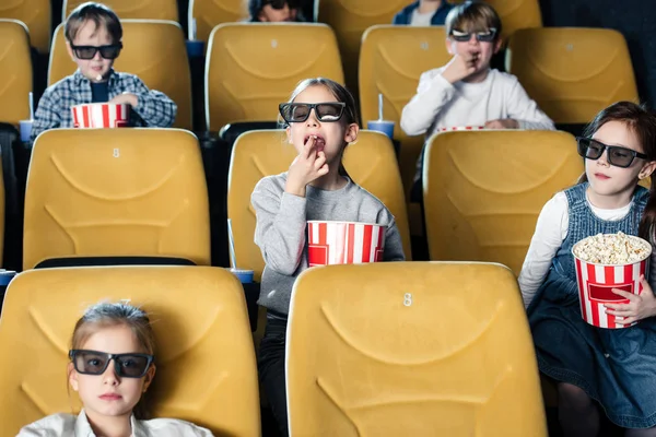 Amigos multiculturales viendo películas en el cine y comiendo palomitas de maíz - foto de stock