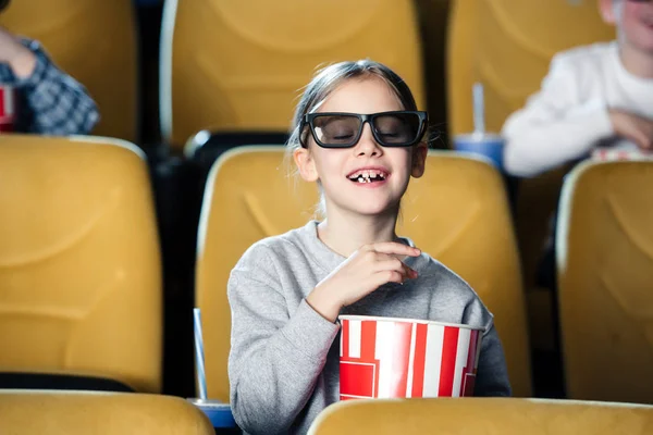 Lindo niño en gafas 3d con los ojos cerrados comiendo palomitas de maíz de la taza de papel - foto de stock