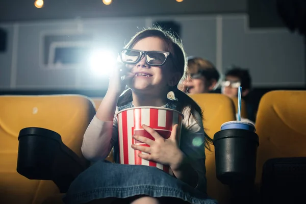 Bonito sorrindo criança em 3d óculos comer pipoca e assistir filme no cinema — Fotografia de Stock