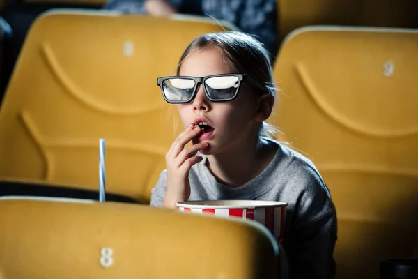 Cute attentive child in 3d glasses eating popcorn in cinema — Stock Photo