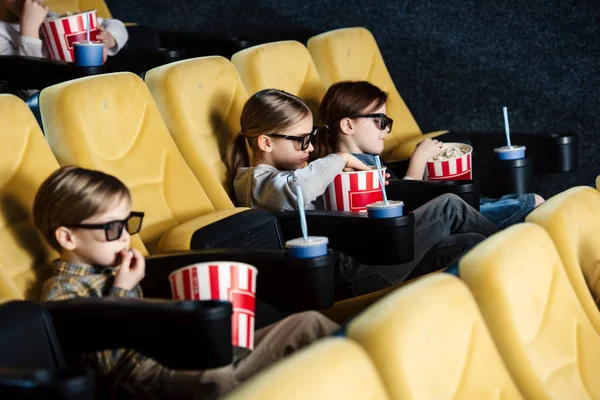 Милые друзья смотрят кино и едят попкорн в кино — стоковое фото