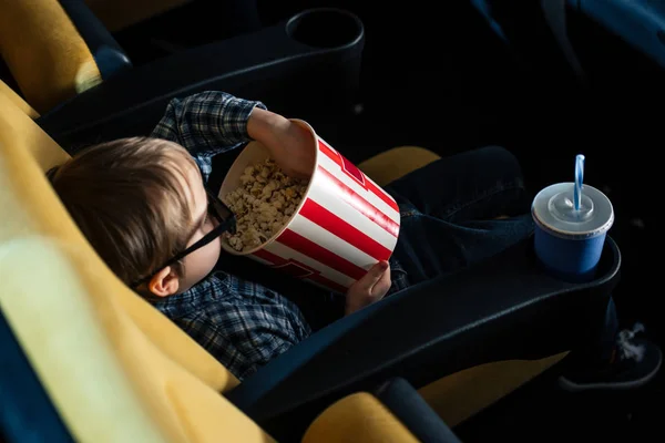 Над головой вид симпатичного мальчика в 3D очках, поедающего попкорн в кино — стоковое фото