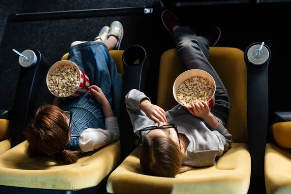 Vista aérea de amigos comiendo palomitas de maíz y viendo películas en el cine - foto de stock