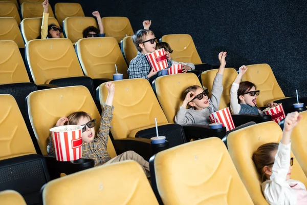 Amigos multiculturales emocionados mostrando el gesto de ganar mientras ven la película juntos - foto de stock