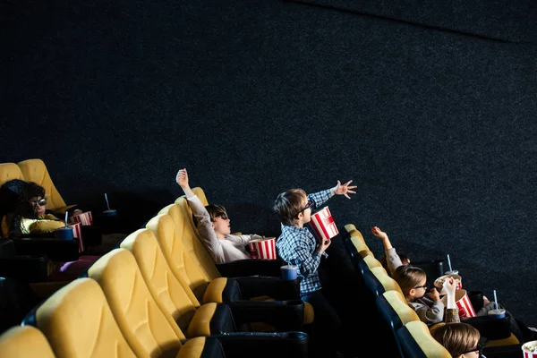Amigos multiculturales viendo películas y comiendo palomitas de maíz en el cine - foto de stock