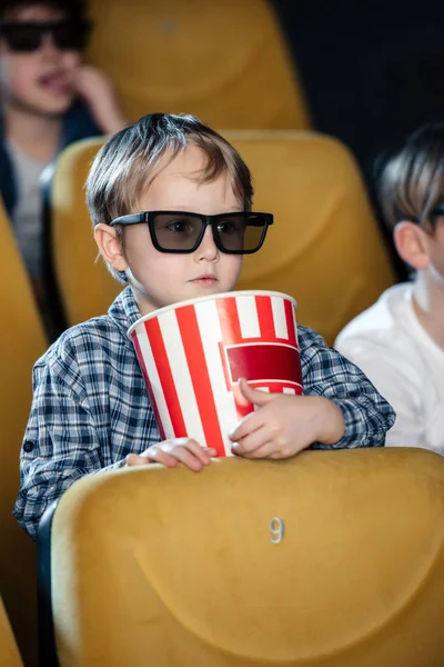 Selective focus of cute bay holding stripped paper cup while watching movie with multicultural friends — Stock Photo