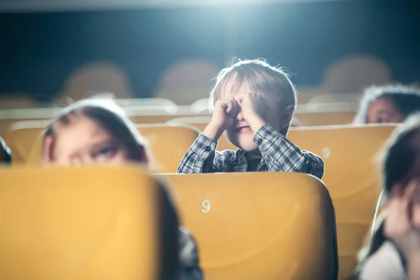 Selektiver Fokus des netten Jungen, der Handgelenke in der Nähe einer Brille hält, während er mit multikulturellen Freunden einen Film anschaut — Stockfoto