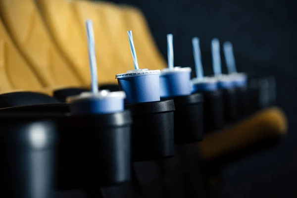 Foyer sélectif des sièges de cinéma avec des tasses jetables bleues dans les porte-gobelets — Photo de stock