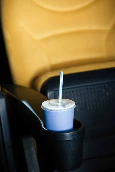 Selective focus of blue disposable cup with straw in cup holder of cinema seat — Stock Photo