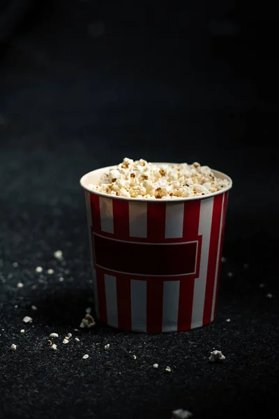 Copo de papel vermelho e branco despojado com pipoca no chão do salão de cinema — Fotografia de Stock