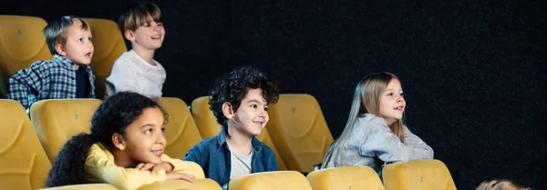 Panoramic shot of multicultural friends spending time in cinema together — Stock Photo