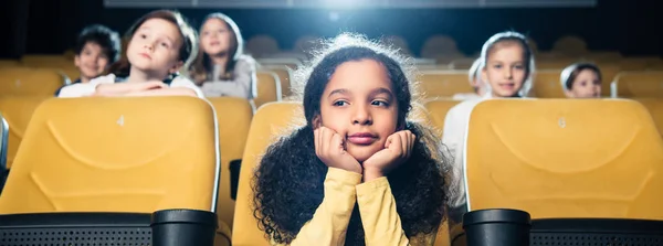 Panoramica di amici multiculturali che guardano film in cinema insieme — Foto stock