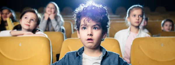 Panoramic shot of multicultural friends in cinema watching movie together — Stock Photo