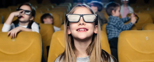 Панорамный снимок улыбающихся друзей в 3D очках, смотрящих фильм вместе — стоковое фото