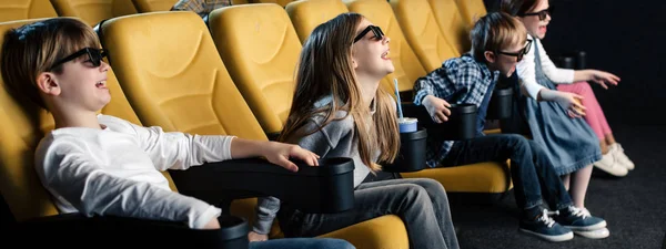 Panoramic shot of exited friends in 3d glasses watching movie together — Stock Photo