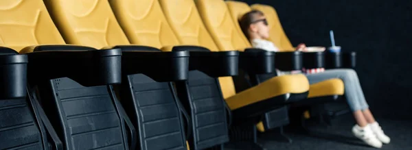 Prise de vue panoramique de sièges cinéma orange avec enfant assis dans des lunettes 3D — Photo de stock