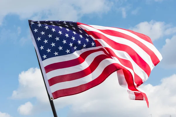 Low angle view of stars and stripes on american flag against blue sky — Stock Photo