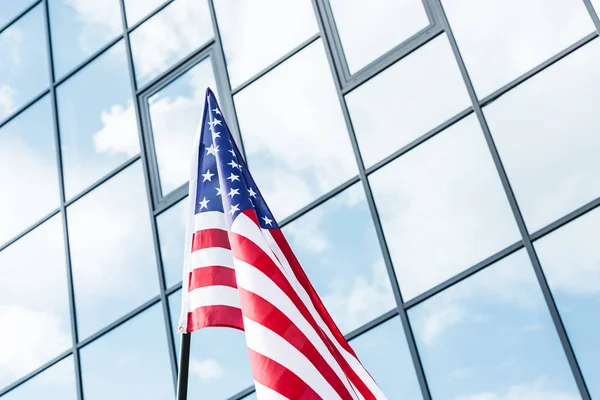Flag of america with stars and stripes near building with glass windows — Stock Photo