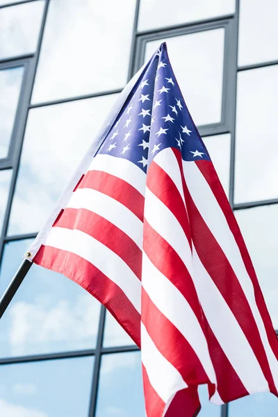 Американський прапор з зірками і смугами біля будівлі зі скляними вікнами — стокове фото