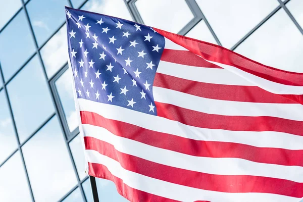 Étoiles et rayures sur le drapeau américain près du bâtiment avec des fenêtres en verre — Photo de stock