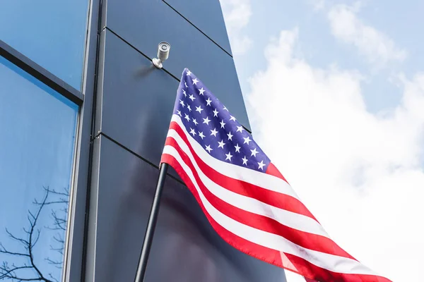 Vista ad angolo basso della bandiera nazionale d'America con stelle e strisce vicino edificio contro cielo blu con nuvole — Foto stock