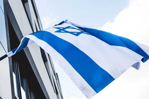 Bajo ángulo de visión de la bandera de Israel con estrella de David cerca de la construcción contra el cielo - foto de stock