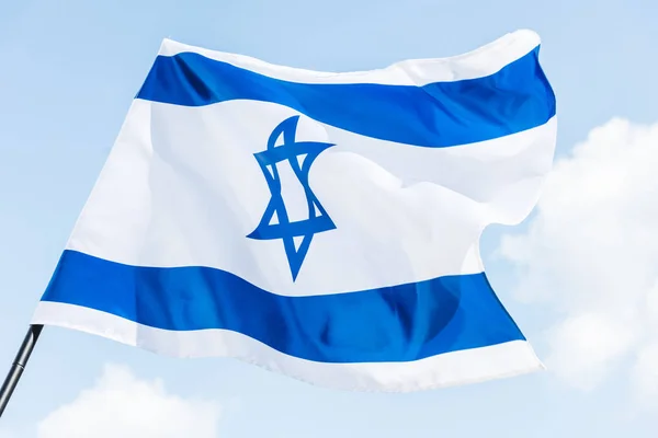 Низкоугольный вид национального флага Израиля со звездой давида на фоне голубого неба — стоковое фото