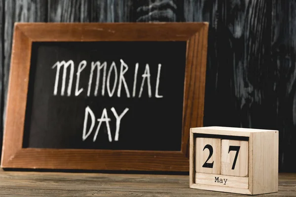 Cubes with date near chalkboard with memorial day lettering on wooden surface — Stock Photo
