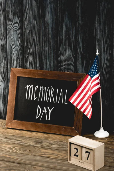 Chalkboard with memorial day lettering near american flag and wooden cubes with date — Stock Photo