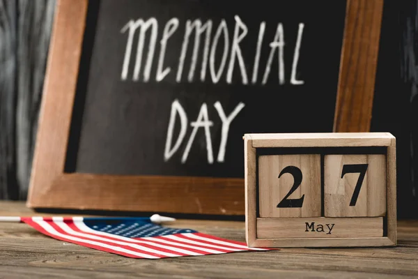 Wooden cubes with date near flag of america with stars and stripes and memorial day lettering on chalkboard — Stock Photo