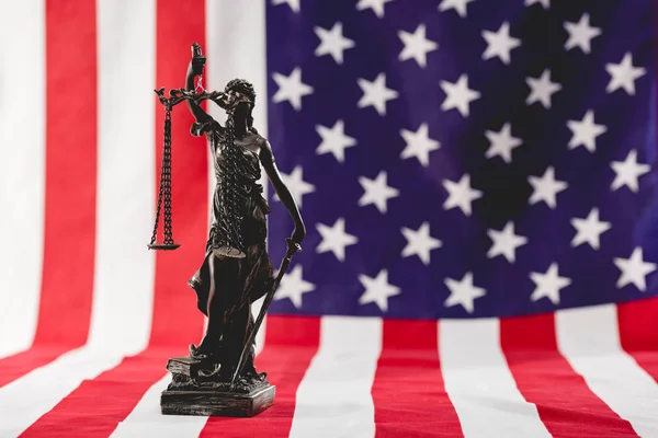 Избирательный фокус статуи правосудия возле американского флага — стоковое фото