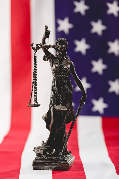 Foco selectivo de la estatua de la justicia cerca de la bandera americana con estrellas y rayas - foto de stock