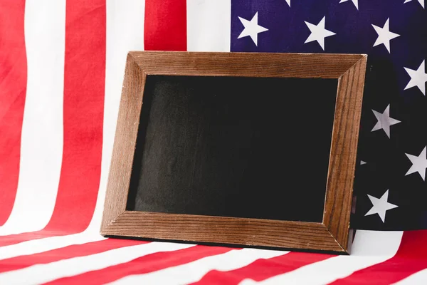 Empty black board near american flag with stars and stripes — Stock Photo