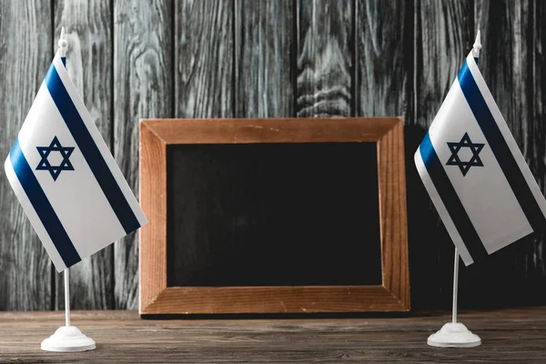 Empty chalkboard near national israel flags with star of david — Stock Photo