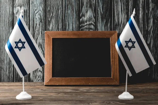 National israel flags with star of david near empty chalkboard — Stock Photo