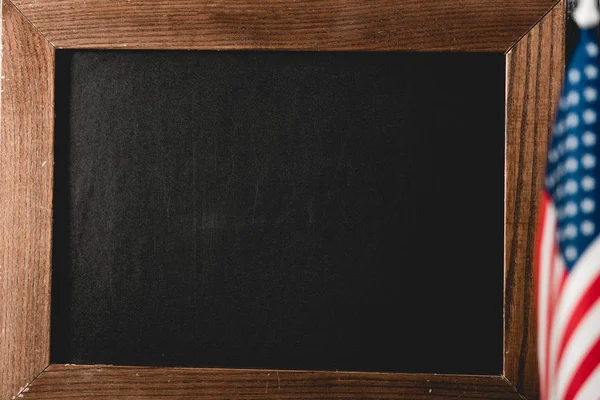 Close up of empty black board near american flag — Stock Photo