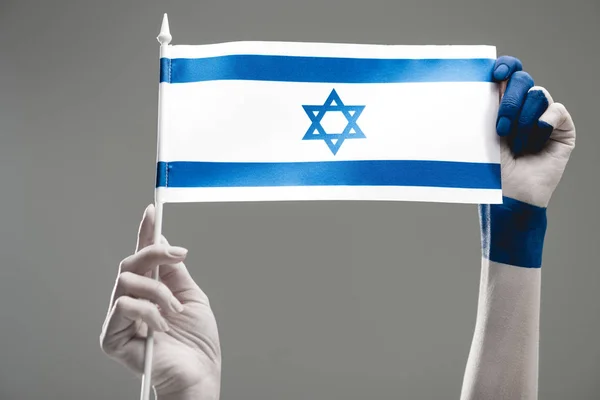 Обрезанный вид женских рук, держащих флаг Израиля на сером — стоковое фото