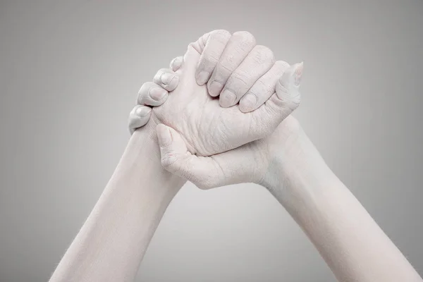 Cropped view of female hands painted in white with clenched hands on grey — Stock Photo