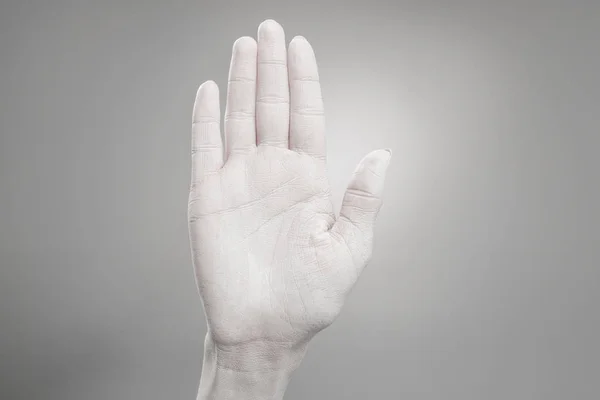 Vista recortada de la mano femenina pintada de blanco sobre gris - foto de stock