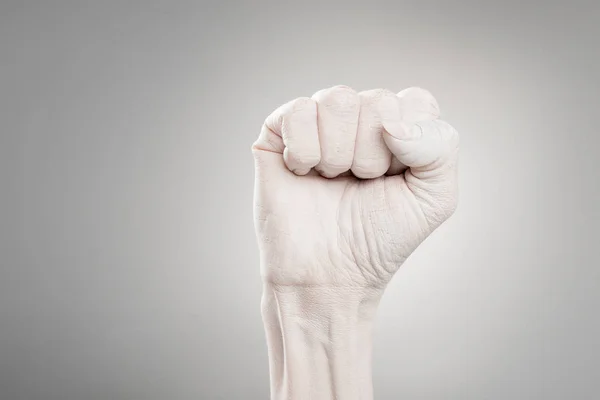 Vue recadrée de la femelle peinte à la main en blanc montrant le poing sur gris — Photo de stock