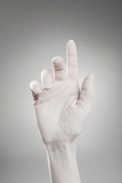 Cropped view of female hand painted in white pointing with finger on grey — Stock Photo