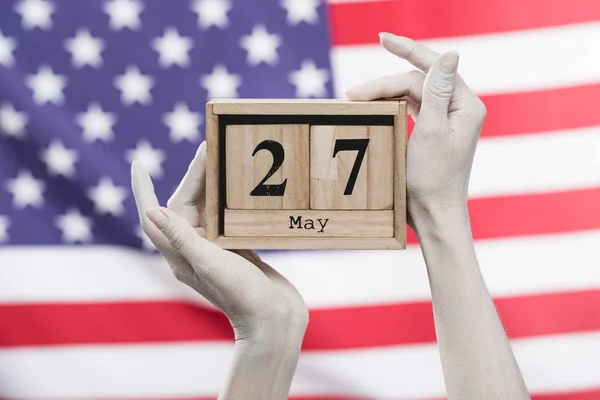 Vue recadrée des mains féminines peintes en blanc tenant des cubes en bois avec la date près du drapeau américain — Photo de stock