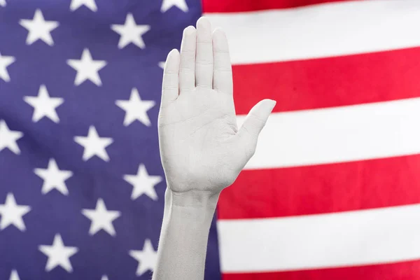 Vista recortada de la mano femenina pintada de blanco cerca de la bandera americana - foto de stock