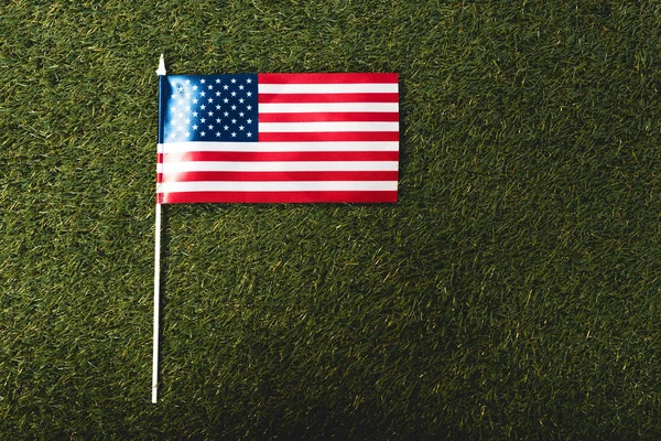 Вид сверху на американский флаг со звездами и полосками на траве — стоковое фото