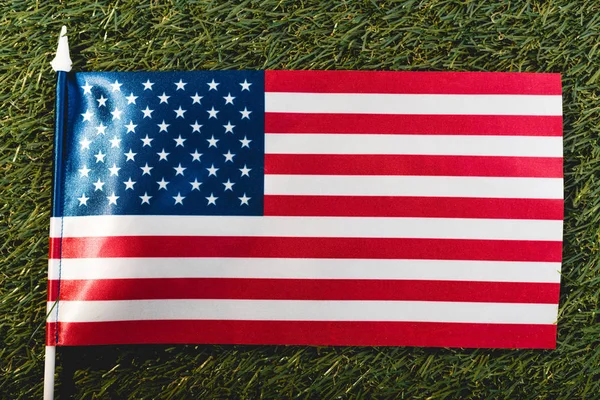 Primer plano de la bandera americana con estrellas y rayas sobre hierba verde - foto de stock