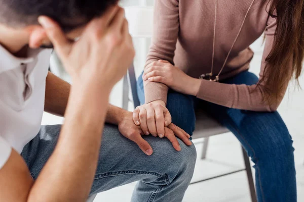 Vue recadrée de la femme tenant la main de l'homme pendant la séance de thérapie de groupe — Photo de stock