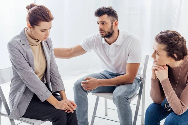 Mann tröstet traurige Frau während Gruppentherapie — Stockfoto