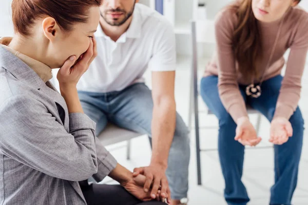 Mujer cubriendo la cara y llorando durante la sesión de terapia de grupo - foto de stock