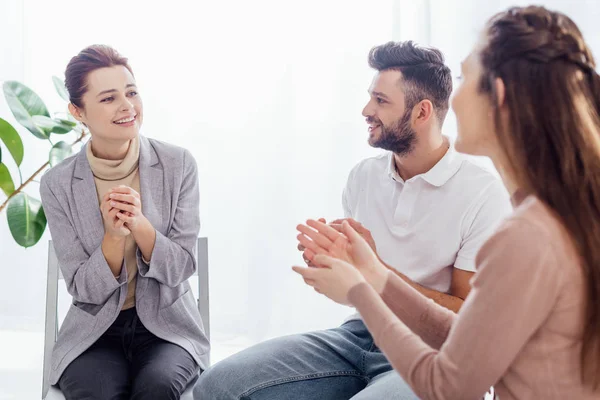 Smiling women and man sitting and applauding during group therapy session — Stock Photo
